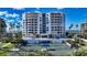 Beautiful shot of the white condo building, showing the entry way, tennis court, and palm trees at 455 Longboat Club Rd # 407, Longboat Key, FL 34228