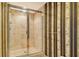 Bathroom featuring a tiled shower with glass door and decorative wallpaper at 455 Longboat Club Rd # 407, Longboat Key, FL 34228