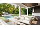 An open concept outdoor living area with a pool, summer kitchen, patio seating, and lush tropical views at 4644 Higel Ave, Sarasota, FL 34242