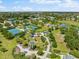 Aerial image of neighborhood park featuring tennis courts, playground, walking paths, and mature trees under a blue sky at 4954 Newport News Cir, Lakewood Ranch, FL 34211