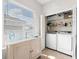 Well-organized laundry room with washer, dryer, shelving and storage and a view of the outside through a bright window at 4954 Newport News Cir, Lakewood Ranch, FL 34211