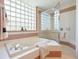 A close up of the bathtub and the shower with a glass block window at 5087 Timber Chase Way, Sarasota, FL 34238