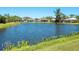 A picturesque view of the tranquil pond surrounded by lush greenery and neighboring houses at 5087 Timber Chase Way, Sarasota, FL 34238