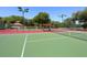 Well-maintained tennis courts featuring green and red surfaces, surrounded by lush greenery and lighting at 5087 Timber Chase Way, Sarasota, FL 34238