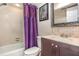 This bathroom offers a bathtub with a purple curtain, toilet, vanity with a mirror, and artwork at 5753 Summer Side Ln # 8A, Sarasota, FL 34231
