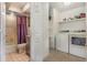 This laundry features a washer and dryer with tile flooring, shelves, and a view into the bathroom at 5753 Summer Side Ln # 8A, Sarasota, FL 34231