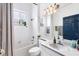 Well-lit bathroom with a white vanity, tiled bath/shower, blue door, and decorative wall mirror at 5806 43Rd E Ct, Bradenton, FL 34203