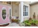 Inviting front porch features a decorative pink door, a cozy bench with pillows, and lush greenery at 5806 43Rd E Ct, Bradenton, FL 34203