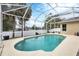 Inviting screened-in pool area with lush landscaping and a concrete patio under a bright blue sky at 5806 43Rd E Ct, Bradenton, FL 34203