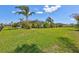 Expansive backyard featuring a lush lawn, mature palm trees, and screened in lanai, perfect for Florida outdoor living at 604 166Th E St, Bradenton, FL 34212