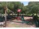 Community playground with a slide, climbing structure, seesaw, covered picnic tables, and mature trees at 604 166Th E St, Bradenton, FL 34212
