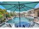 Relaxing pool view featuring an umbrella and sun loungers, with privacy provided by lush landscaping at 604 166Th E St, Bradenton, FL 34212