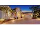 Elegant single-story home with a brick driveway, well-lit exterior, and lush landscaping at dusk at 7340 Barclay Ct, University Park, FL 34201