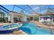 Backyard screened pool featuring a brick patio, spa, and comfortable lounge chairs for ultimate relaxation and entertaining at 7340 Barclay Ct, University Park, FL 34201