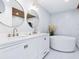 Modern bathroom with double sinks, white cabinets, marble walls and sleek soaker tub at 749 Tropical Cir, Sarasota, FL 34242