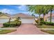 Charming single-story home with a red brick driveway and tropical landscaping at 7655 Pesaro Dr, Sarasota, FL 34238