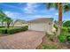 Exterior view of a charming home with a brick driveway and mature palm trees at 7655 Pesaro Dr, Sarasota, FL 34238