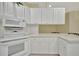 Well lit kitchen with a white stovetop, stainless steel microwave, and white countertops at 7655 Pesaro Dr, Sarasota, FL 34238