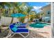 Lounge poolside while soaking up the sun in the backyard featuring a pool, lush landscaping, and resort-style seating at 785 Jacaranda Rd, Anna Maria, FL 34216
