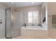 Bright bathroom featuring a large tub, glass-enclosed shower, and a window with plantation shutters at 8227 37Th Avenue W Cir, Bradenton, FL 34209