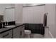 Well-lit bathroom with modern black granite vanity and shower with neutral colored curtain at 8521 Canyon Creek Trl, Parrish, FL 34219