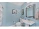 Charming powder room with a pedestal sink, ornate mirror, and soft blue walls at 9203 Griggs Rd # A302, Englewood, FL 34224