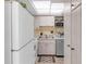 Compact kitchen featuring white appliances, light wood-grain cabinets, and a modern countertop at 94 Strathmore Blvd, Sarasota, FL 34233