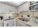 Well-lit kitchen featuring white cabinets, modern appliances, double stainless steel sink, and neutral countertops at 94 Strathmore Blvd, Sarasota, FL 34233