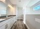 Bright bathroom with a double vanity, window in the shower, and wood-look flooring at 10006 Degas Ter, Bradenton, FL 34212