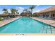 Community pool surrounded by lots of blue lounge chairs, tropical landscaping, and a black fence at 1009 3Rd E St, Palmetto, FL 34221