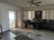 View of the living room with tile floors, ceiling fan, sliding glass door, vertical blinds, and clutter at 10443 Keystone St, Spring Hill, FL 34608
