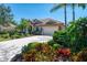 Beautiful single-story home featuring lush landscaping, mature palms, and a spacious driveway leading to an attached two-car garage at 107 Wayforest Dr, Venice, FL 34292