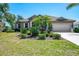 Charming single-story home featuring mature landscaping, a tile roof, and a spacious driveway leading to an attached two-car garage at 107 Wayforest Dr, Venice, FL 34292