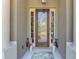 Elegant front entrance featuring a beautiful glass-paneled door flanked by sidelights and stylish potted plants at 107 Wayforest Dr, Venice, FL 34292