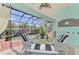 Cozy screened-in patio with a dining table set for four overlooks the sparkling pool area at 107 Wayforest Dr, Venice, FL 34292
