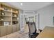Well-lit home office with built-in bookcase, french doors, and comfortable workspace at 11835 Hollyhock Dr, Lakewood Ranch, FL 34202