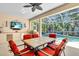 Covered patio with dining table, ceiling fan, tv, and built-in grill overlooks screened pool at 11835 Hollyhock Dr, Lakewood Ranch, FL 34202