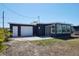 Rear exterior of home featuring an attached garage, tiled patio, and sunroom with ample windows at 125 Palmetto Ne Cir, Port Charlotte, FL 33952