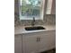 Close-up of a kitchen sink with quartz countertops and mosaic backsplash at 1804 Bayshore Gardens Pkwy, Bradenton, FL 34207