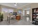 Bright living room with large windows, neutral paint and ceiling fan. Furnished with a stylish desk, chair, and bookshelf at 2207 Holyoke Ave, Bradenton, FL 34207