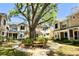 View of townhomes with manicured landscaping, mature trees and a bench for residents at 2409 Gun Flint Trl, Palm Harbor, FL 34683