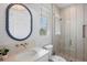 Stylish bathroom featuring a glass shower and blue framed oval mirror at 244 Willow Ave, Anna Maria, FL 34216