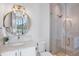 Modern bathroom with glass-enclosed shower, decorative tile, round mirror, and marble countertop at 244 Willow Ave, Anna Maria, FL 34216
