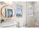 Bright bathroom with marble countertop, round mirror, glass shower, and a window view at 244 Willow Ave, Anna Maria, FL 34216