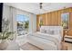 Bright bedroom boasts a wood accent wall, plush bedding, and private balcony access at 244 Willow Ave, Anna Maria, FL 34216