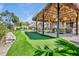Backyard entertainment area with a putting green, cozy seating and multiple tiki huts, perfect for relaxation and fun at 244 Willow Ave, Anna Maria, FL 34216