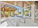 Covered patio with a ping pong table, tiki hut, outdoor seating, and a serene pool, ideal for relaxation and entertainment at 244 Willow Ave, Anna Maria, FL 34216