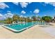Large community swimming pool surrounded by lounge chairs, palm trees, and lush landscaping under a blue sky at 3009 Live Oak Ln # 33, Palmetto, FL 34221