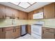 Functional kitchen featuring wooden cabinetry, white appliances, and a skylight at 314 Signorelli Dr, Nokomis, FL 34275