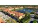 Aerial of a community featuring terracotta-roofed townhomes surrounding a lake with a fountain and a swimming pool at 3456 Parkridge Cir # 33-105, Sarasota, FL 34243